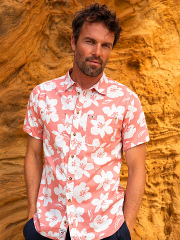 Man wearing a pink floral shirt against a textured orange wall
