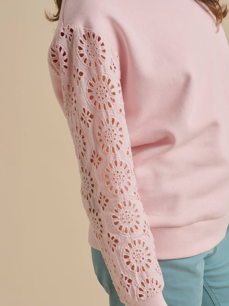Pink sweater with lace sleeves on a beige background