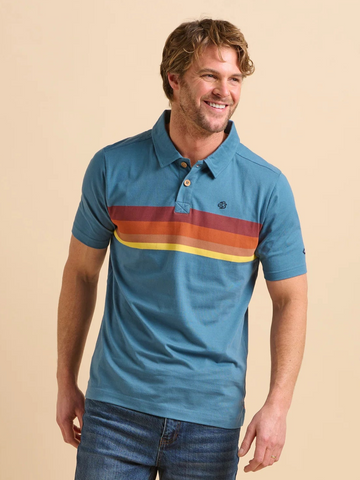 Man wearing a blue polo shirt with colorful stripes and jeans on a beige background